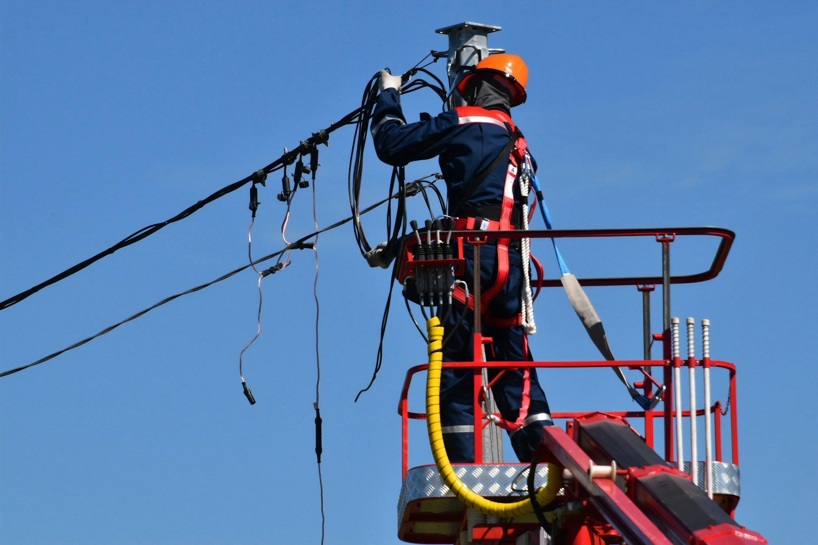 A utility worker repairing overhead power lines from a bucket truck